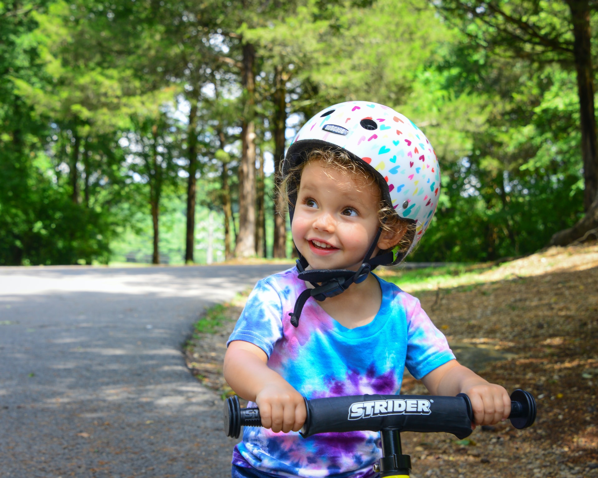 A toddler riding a scooter with a helmet on