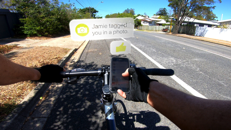 Bike rider holding mobile phone while on bike on the road