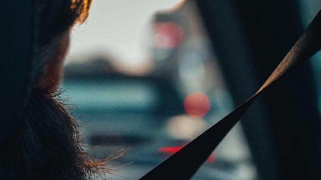 A closed up back shot of a driver with the seatbelt on