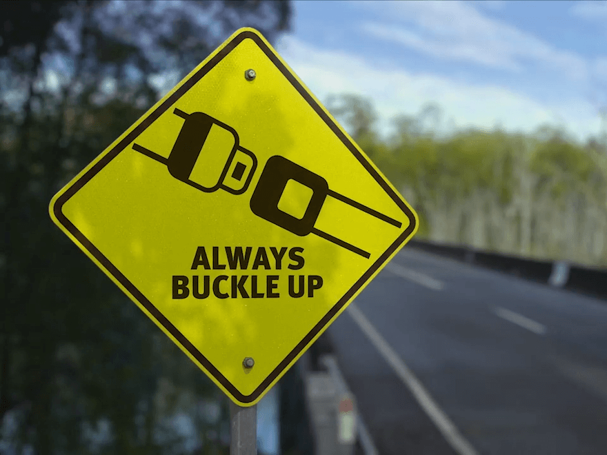 A yellow road sign that says 'Always buckle up'
