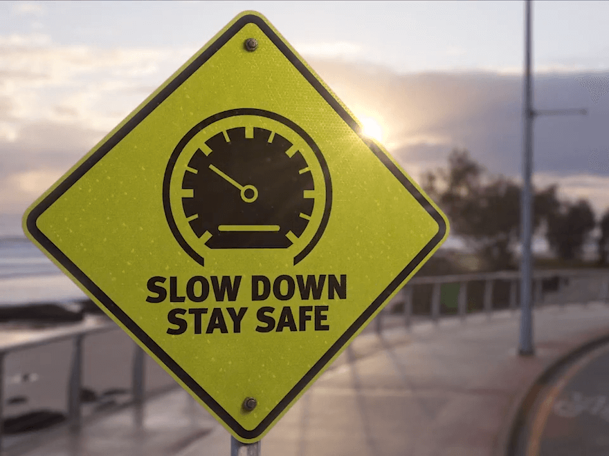 A yellow road sign says 'Slow down and stay safe'