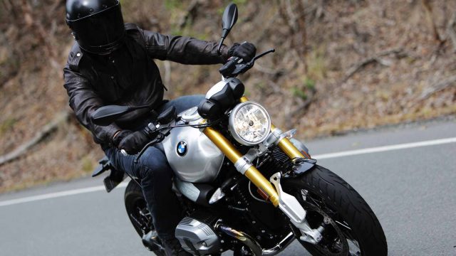 Close up shot of motorcyclist riding on a road in front of the bush