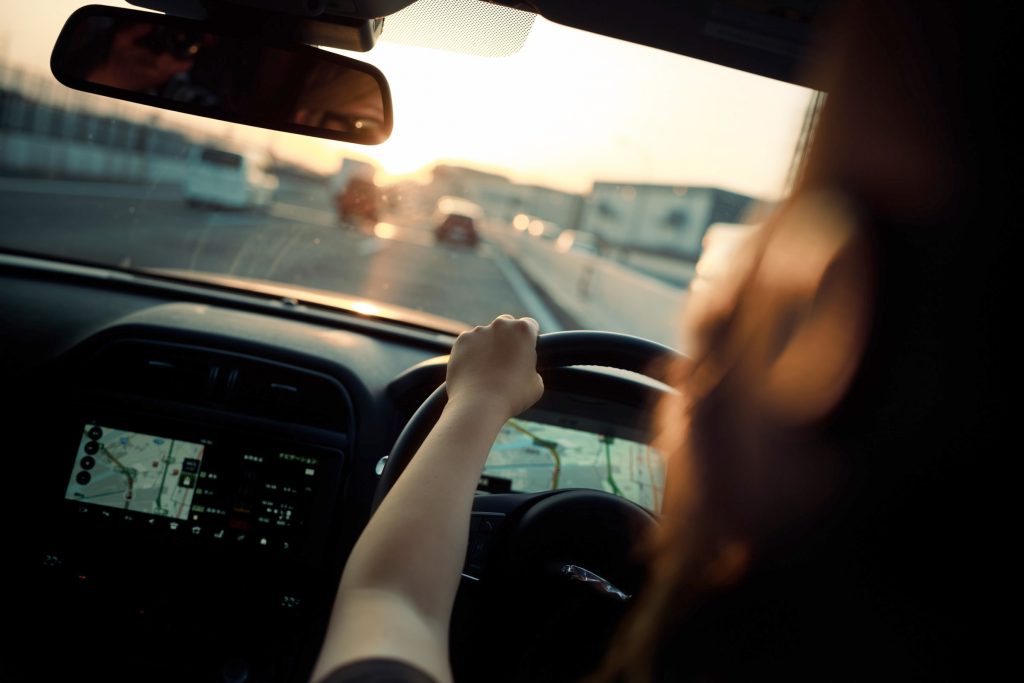 Woman driving on a highway as the sun is setting