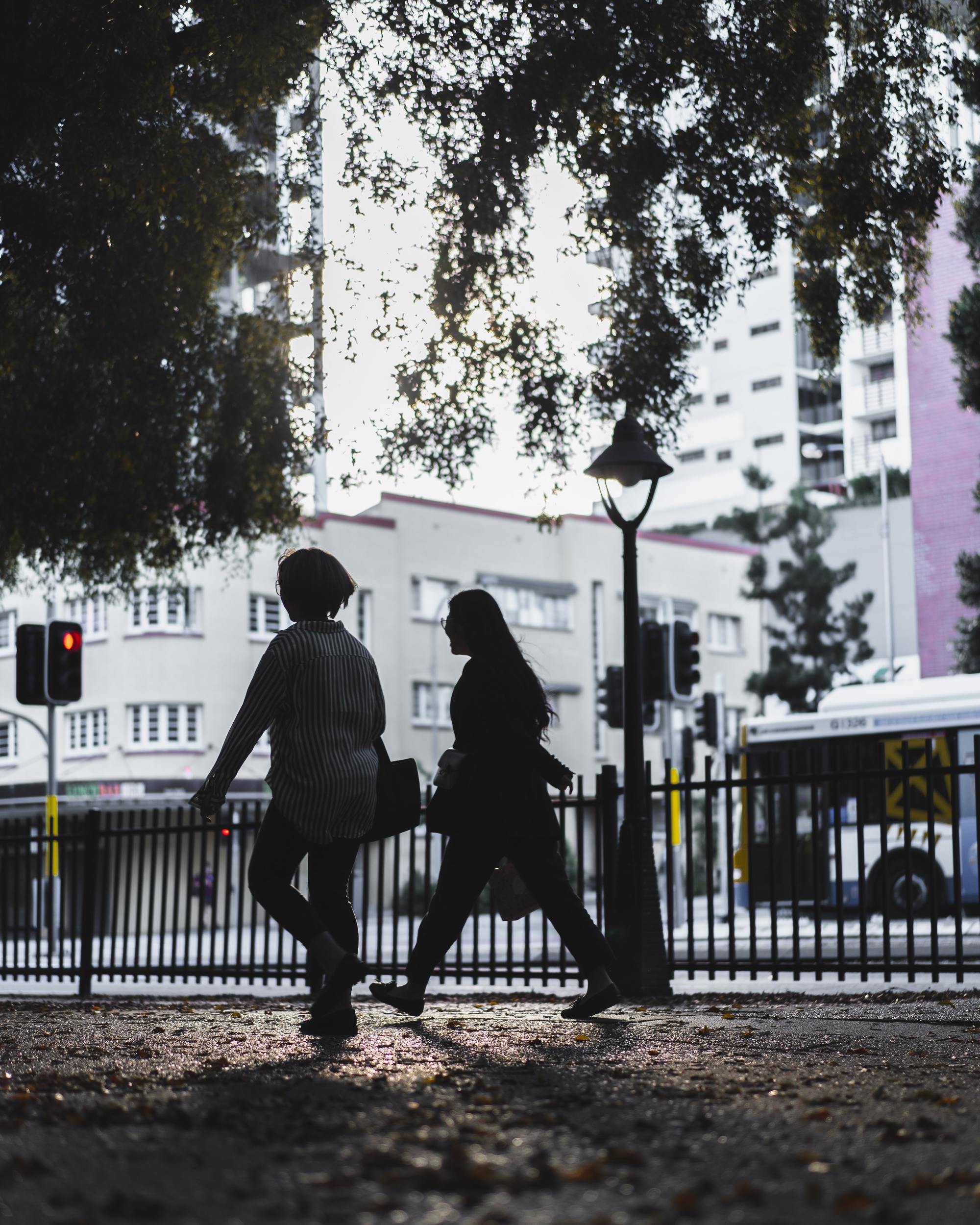 Two pedestrians walking alongside busy road