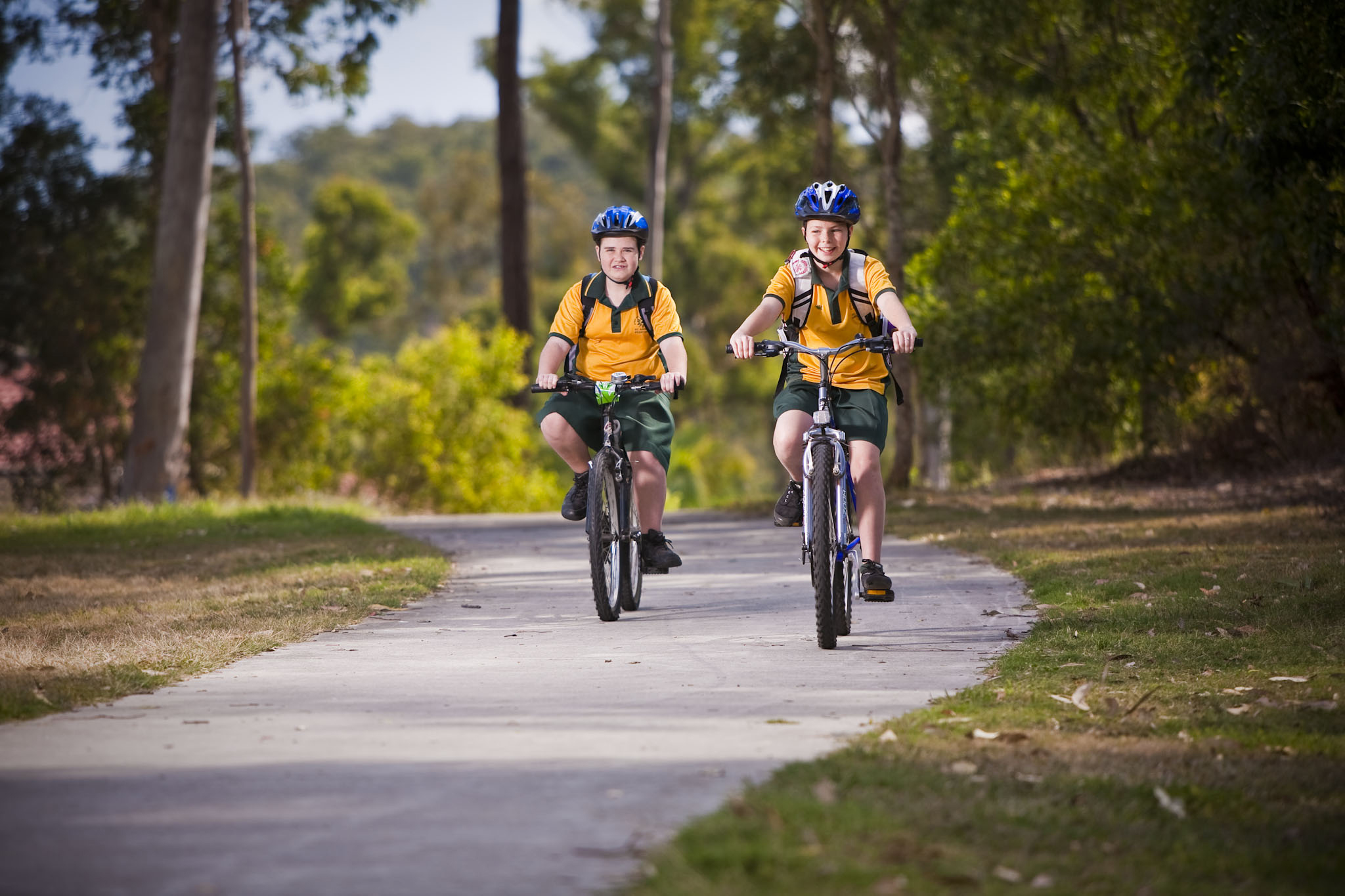 Two school children riding bikes on a footpath