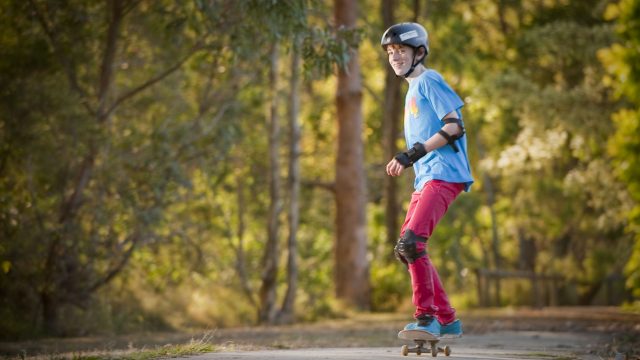 Teenager riding a skateboard wearing protective gear