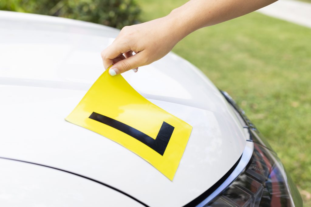 Learner driver applying an L-plate to their car