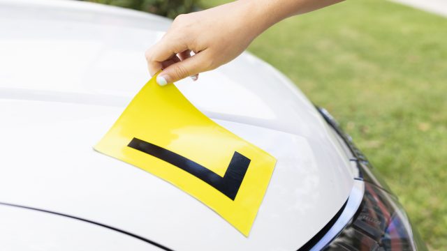 Learner driver applying an L-plate to their car