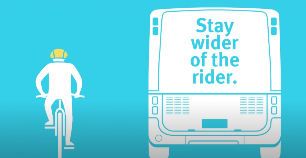 A graphic of a bike rider next to a bus that says 'Stay wider of the rider.'