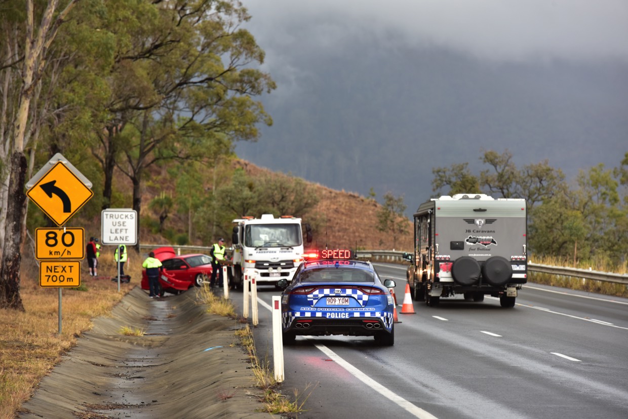 A blue police car parked at the curb on a busy highway