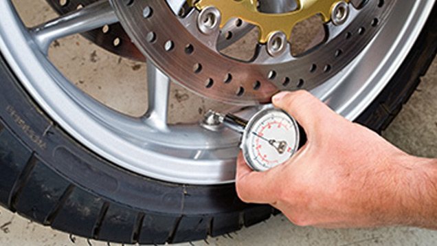 Checking tyre pressure on motorbike